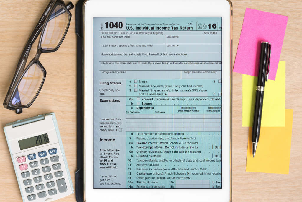 Carta de correção de nota fiscal na tela de um tablet, em inglês. Ao redor do tablet: uma caneta, post-its, calculadora e óculos de grau ao redor
