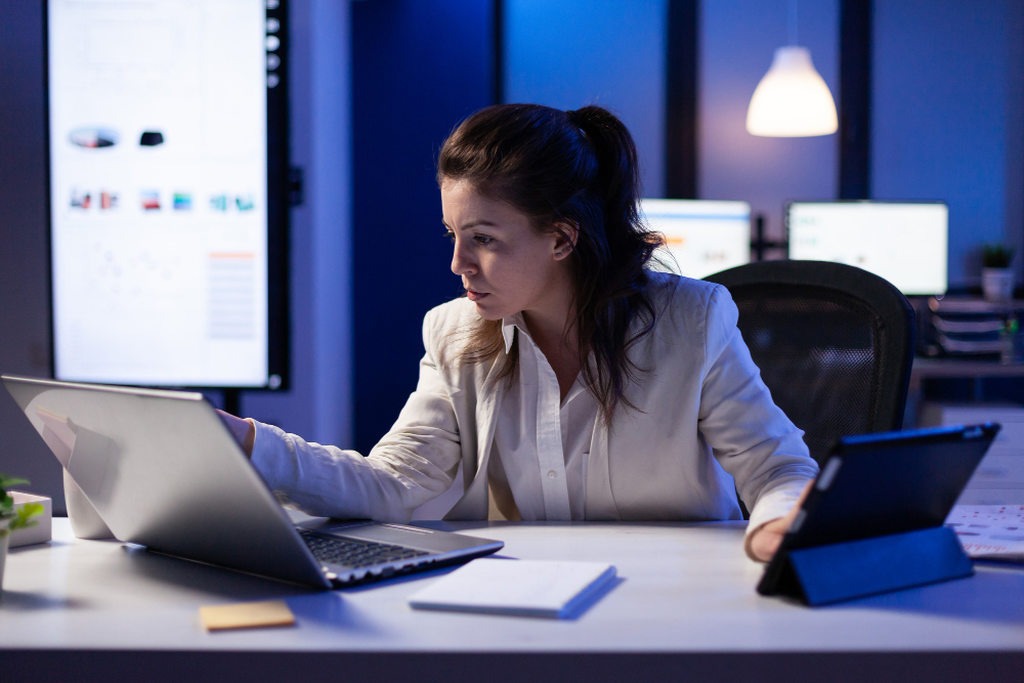 Mulher com roupa social usando notebook em escritório moderno, simbolizando nota fiscal eletrônica