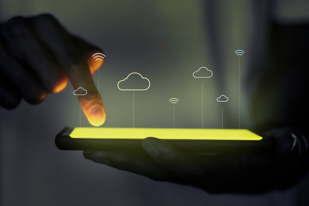 Pessoa tocando em tela de um celular, cujo está com efeitos digitais de nuvens e símbolo de wifi saindo dele, representando notas fiscais salvas em nuvem