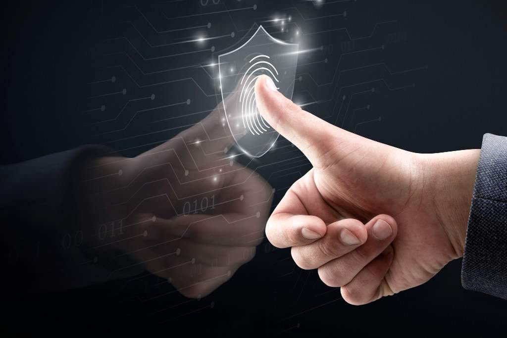 Pessoa tocando polegar num símbolo digital de biometria, representando segurança digital